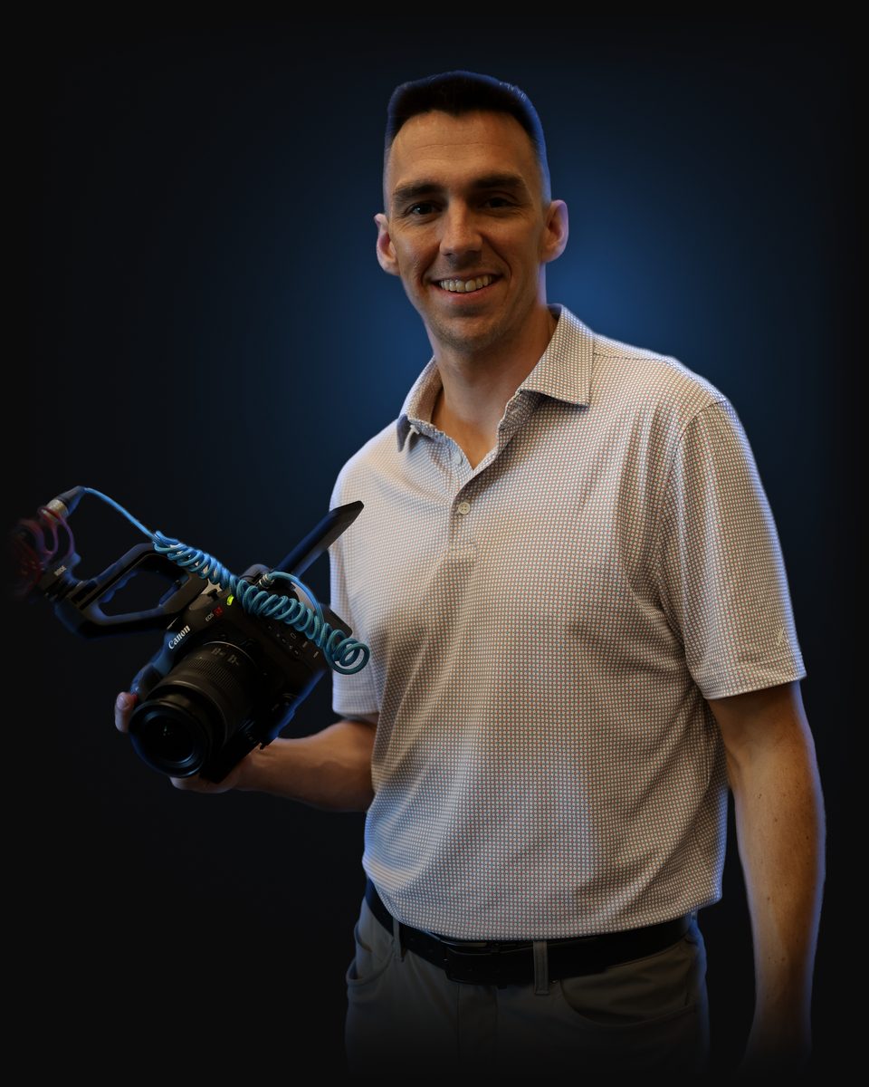 Andrew Rusk smiling and holding a Canon camera rigged with a RØDE shotgun mic